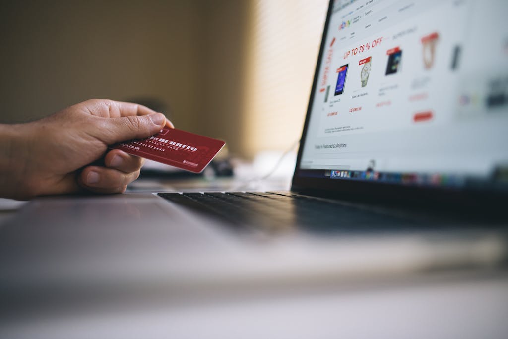 Person holding a credit card while shopping online on a laptop, indicating ecommerce transactions. ankara e-ticaret web sitesi yapimi ve paketleri