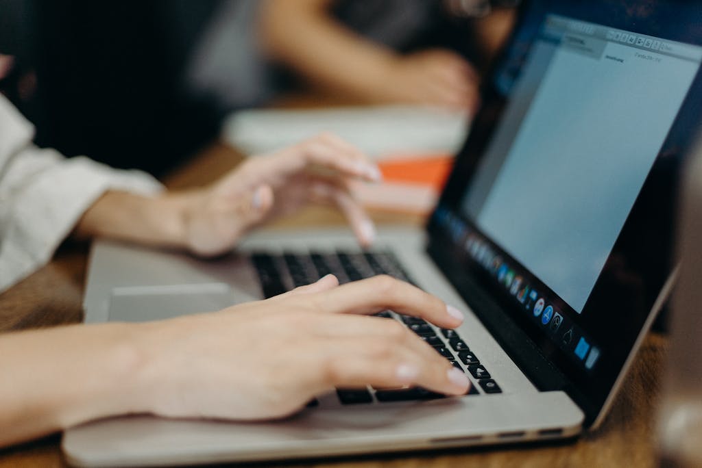 Person typing on a laptop in an office setting. Focus on hands and keyboard. cankaya-web-tasarim